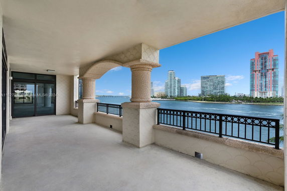 Covered balcony area with decorative columns offering a view of water and distant city buildings.