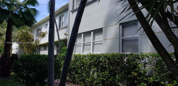 Side view of a two-story building with multiple windows and plants in front.