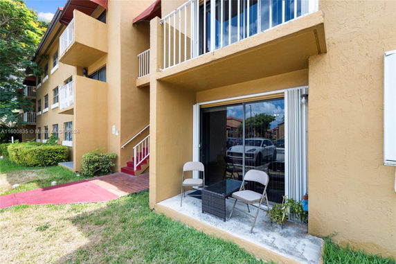 Ground-level view of a multi-story residential building with balconies and glass sliding doors.
