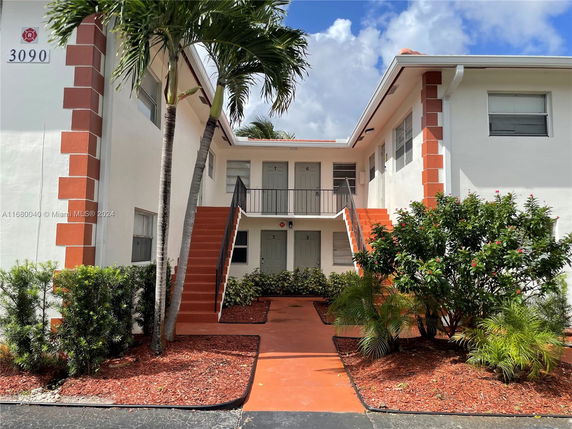 Front view of a two-story residential building with external staircase and red accents.