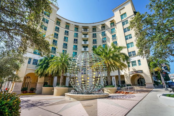 Front view of a multi-story building with a decorative globe structure in front.