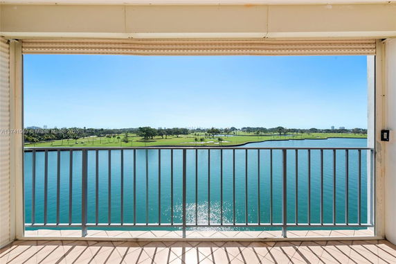 View of a balcony overlooking a lake and green landscape.