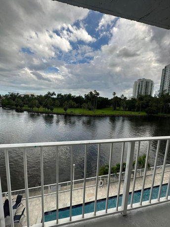 View from a balcony showing a body of water with trees and tall buildings in the distance.