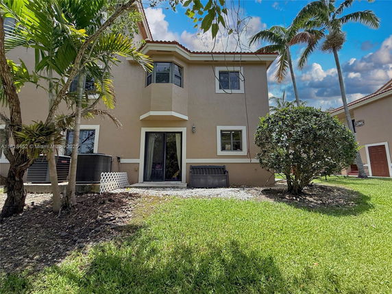 Rear view of a two-story house with beige exterior and several windows.