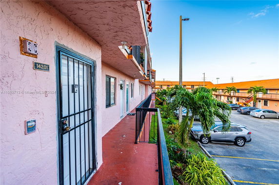View of apartment building exterior with adjacent parking lot.