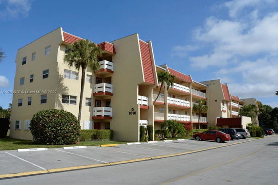 Front view of a multi-story residential building with balconies and red accents.