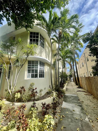 Front view of a multi-story building with large windows and surrounding palm trees.