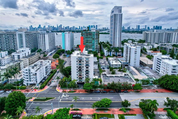 Aerial view of a cityscape with multiple residential buildings and a waterfront in the background.