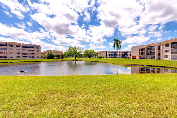 View of a pond with multi-story buildings in the background.