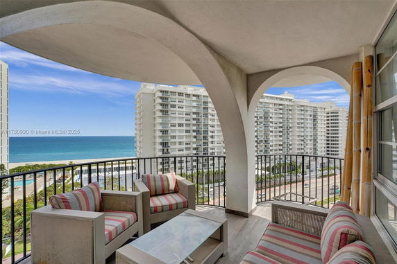 Balcony view overlooking ocean and nearby buildings.