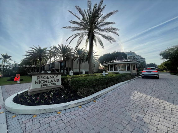 Front view of a multi-story building with palm trees and a welcome sign at the entrance.