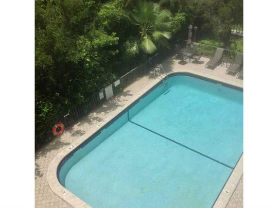 Top view of a swimming pool surrounded by trees and lounge chairs.