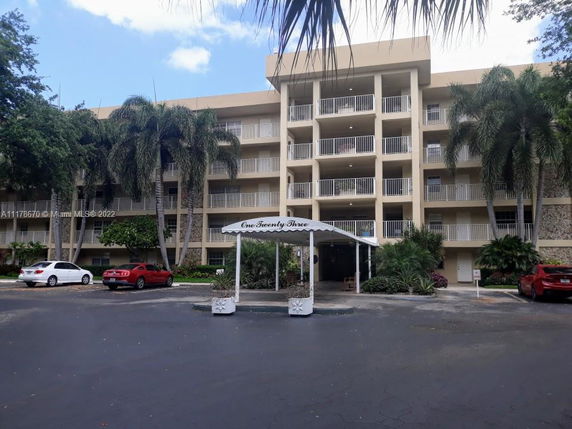 Front view of a multi-story residential building with balconies and a canopy-covered entrance.