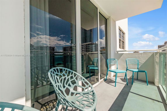 Balcony with chairs overlooking cityscape buildings and ocean.