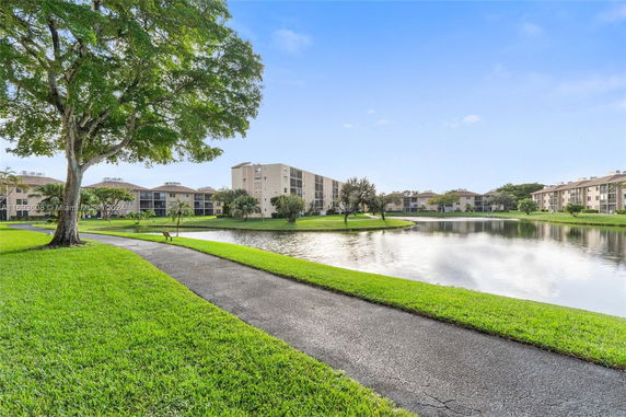 Long view of apartment buildings near a pond with surrounding greenery.