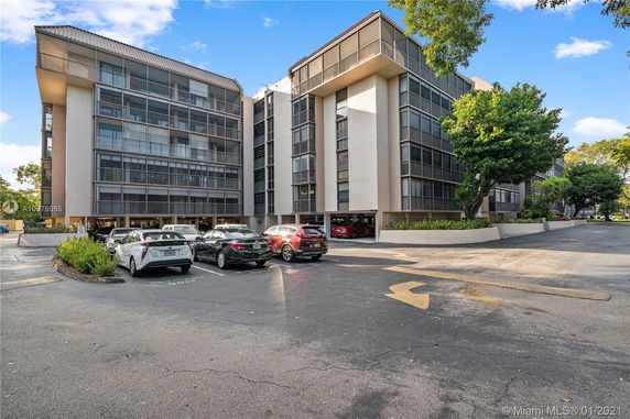 Front view of a multi-story building with a parking lot in front.