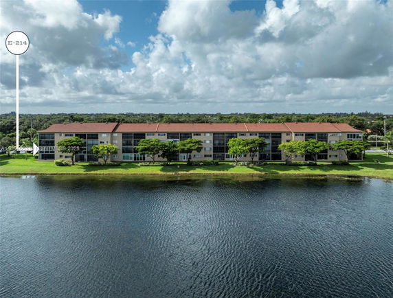 Exterior view of a multi-story residential building with red roofs near a water body.