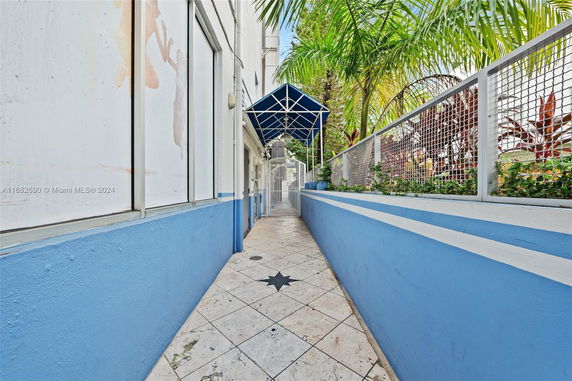 Outdoor path with blue and white walls leading to a gated entrance.