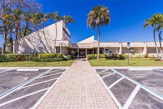Front view of a building with a unique angled roof design and a wide pathway leading to the entrance.