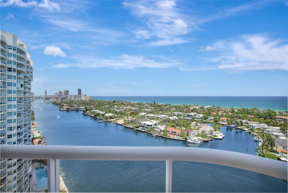 Panoramic view of coastal area with a river, buildings, and ocean in the background.