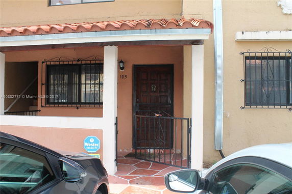 Front view of a residential building with a gated entrance and tiled roof.