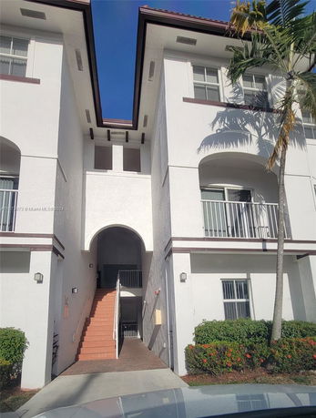 Front view of a multi-story building with an arched entrance and staircase.