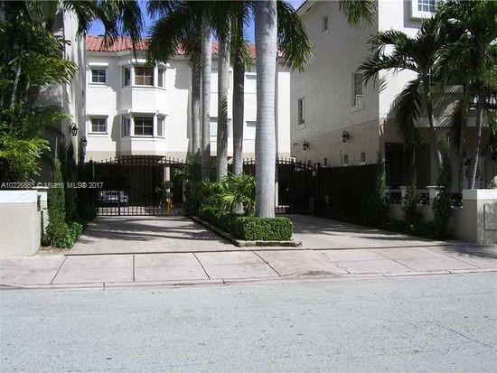 Front view of a multi-story house with a gated entrance and palm trees.