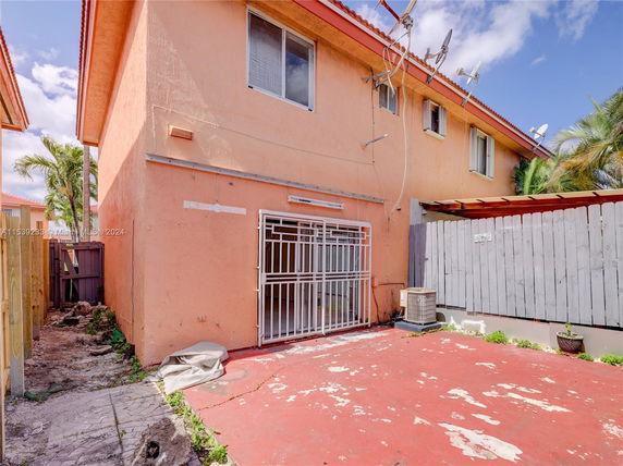 Side view of a two-story building with multiple satellite dishes and a gated entrance.