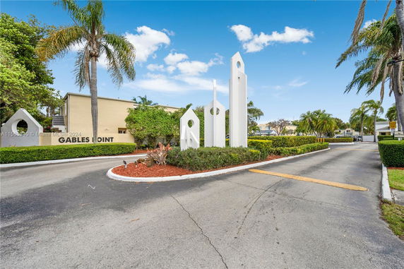 Front view of a residential building with a sign and tall sculptures at the entrance.