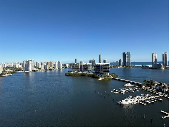 Panoramic view of a coastal cityscape with high-rise buildings and a marina.