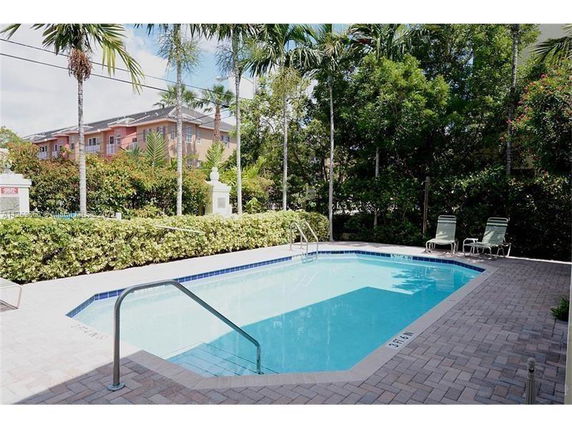 Outdoor swimming pool with surrounding foliage and poolside chairs.
