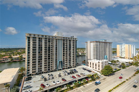 Front view of a multi-story residential building with a parking area below.