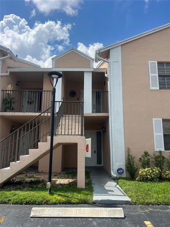 Front view of a two-level residential building with external staircase and balcony.