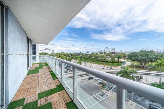 Balcony view overlooking city streets and a park with a Ferris wheel in the distance.