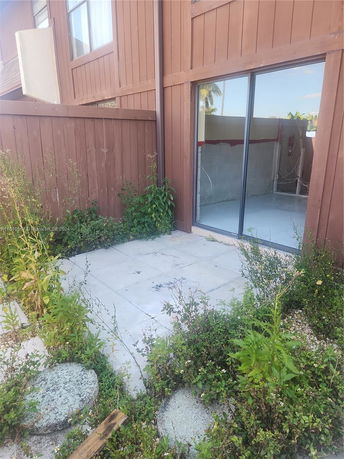Exterior view showing a section of a brown wooden house with sliding glass door.