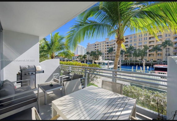 View from a balcony towards a canal and apartment buildings with palm trees.