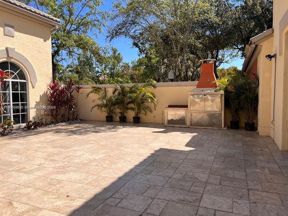 Outdoor patio area with tiled flooring and built-in barbecue grill.