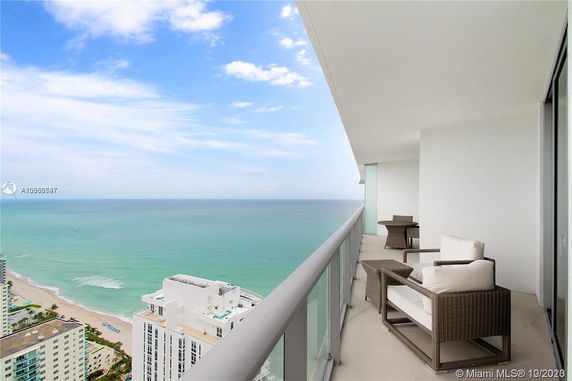 View from a high-rise balcony overlooking the ocean and nearby buildings.