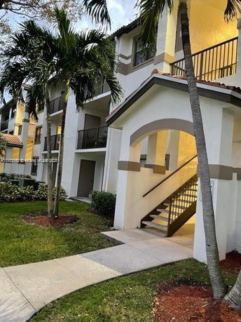 Front view of a multi-story building with balconies and an exterior staircase entrance.