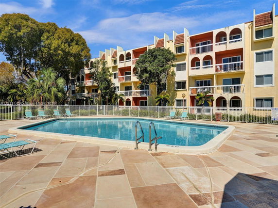 Outdoor swimming pool in front of a multi-story residential building.
