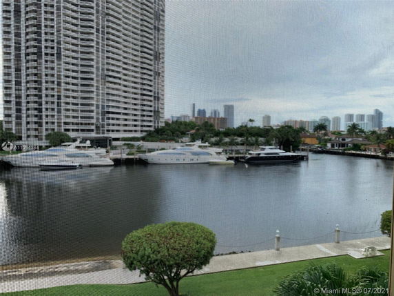 View of tall residential buildings near a waterfront with boats docked along the shore.