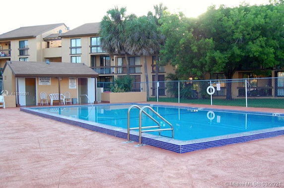 Outdoor swimming pool area next to multi-story residential building.