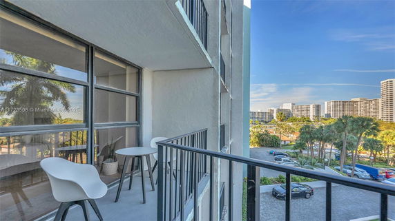 Balcony view of adjacent buildings with a railing and chairs.