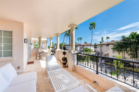 View from a balcony overlooking buildings with terracotta roofs and palm trees.