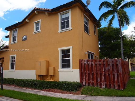Front view of a two-story house with a fenced area on the side.