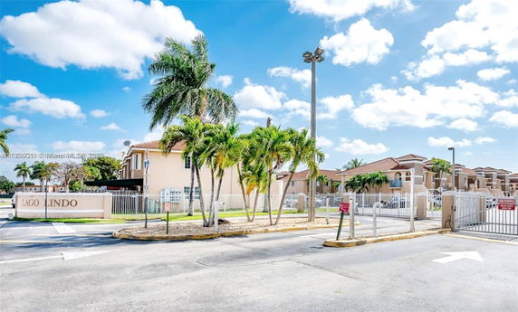 Front view of a gated residential complex with palm trees and a sign reading 'Lago Lindo.'
