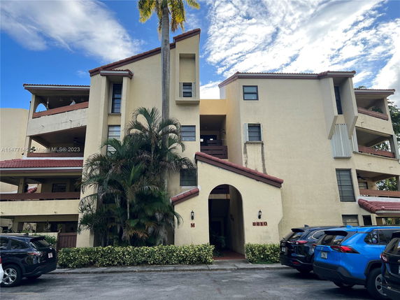 Front view of a multi-story residential building with balconies and tiled roof.