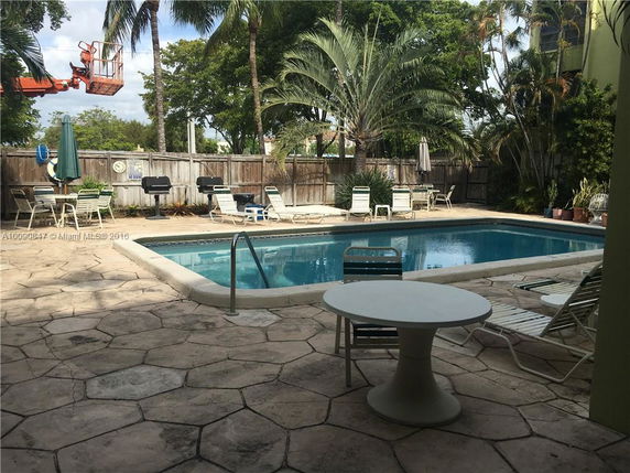 Outdoor patio area with a swimming pool surrounded by lounge chairs and tables.