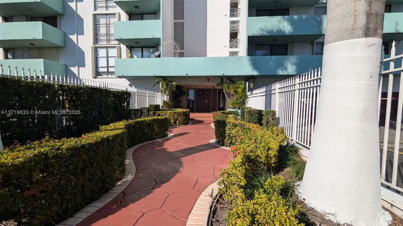 Front view of a multi-story building with balconies and a walkway leading to the entrance.