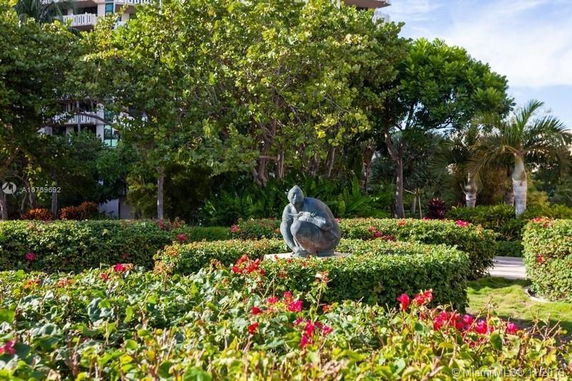 Garden area with a statue, surrounded by trees and flowers.